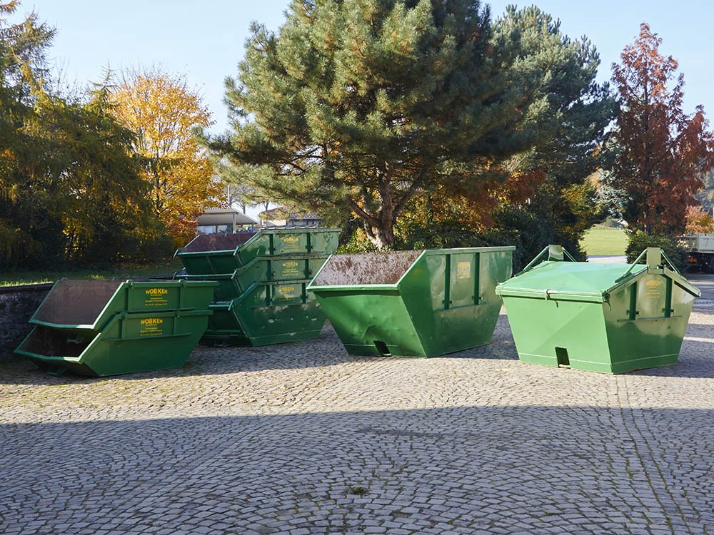 Mulden und Container in verschiedenen Größen in Melle Mehrere grüne Mulden und Container von Wobker Baustoffe e.K. in unterschiedlichen Größen auf dem Betriebshof in Melle