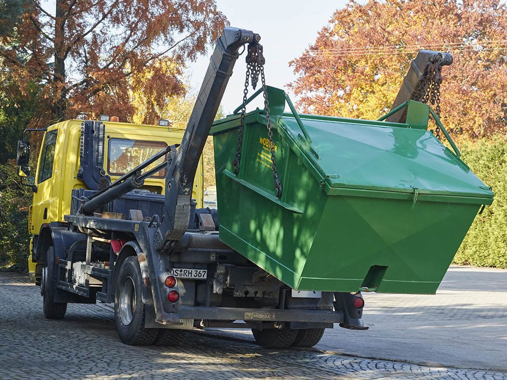 Containerdienst in Melle – Absetz-LKW mit geschlossener Mulde | Wobker Baustoffe Absetz-LKW von Wobker Baustoffe beim Aufnehmen einer geschlossenen Container-Mulde in Melle